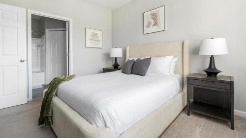 a white bedroom with a large bed and two lamps at Landing - Modern Apartment with Amazing Amenities (ID1374X806) in Charlotte