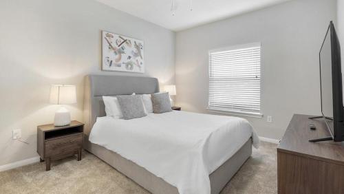 um quarto branco com uma cama e uma televisão de ecrã plano em Landing - Modern Apartment with Amazing Amenities (ID7253X29) em San Antonio