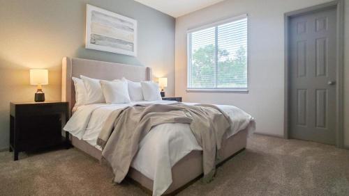 um quarto com uma cama com lençóis brancos e uma janela em Landing - Modern Apartment with Amazing Amenities (ID5166X12) em Denver