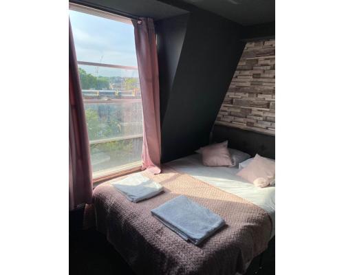 a bed with two towels on it next to a window at Amsterdam Hotel in London