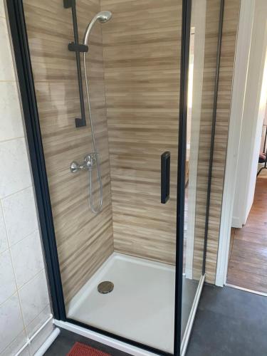 La salle de bains est pourvue d'une douche avec une porte en verre. dans l'établissement Petite maison de vacances, à Fécamp