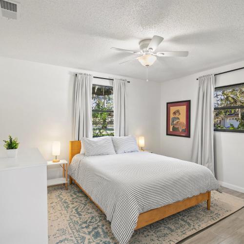 Modern Vacation home near Siesta Key & Downtown في ساراسوتا: غرفة نوم بيضاء مع سرير ومروحة سقف
