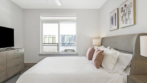 a white bedroom with a bed and a television at Landing - Modern Apartment with Amazing Amenities (ID9880X69) in San Antonio