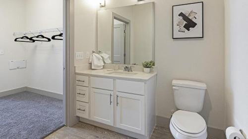 a bathroom with a toilet and a sink and a mirror at Landing - Modern Apartment with Amazing Amenities (ID9880X69) in San Antonio