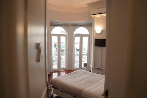 a bedroom with two windows and a bed in a room at Bisengototo Homestay in Lisbon