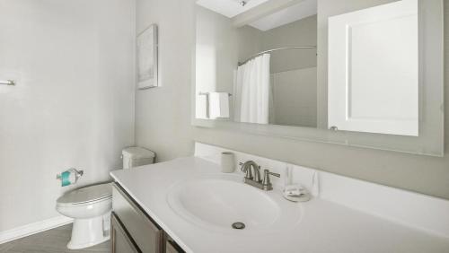 uma casa de banho branca com um lavatório e um WC em Landing - Modern Apartment with Amazing Amenities (ID1245X807) em League City
