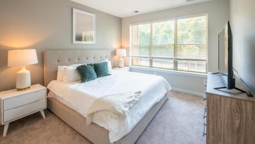 een slaapkamer met een bed, een televisie en een raam bij Landing - Modern Apartment with Amazing Amenities (ID4177X58) in Owings Mills