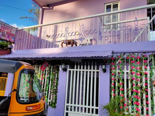 un autobús amarillo estacionado frente a una casa con flores en Purple Guesthouse, en Nasugbu