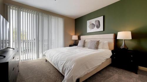 una camera da letto con un grande letto bianco e pareti verdi di Landing - Modern Apartment with Amazing Amenities (ID8572X47) a Las Vegas