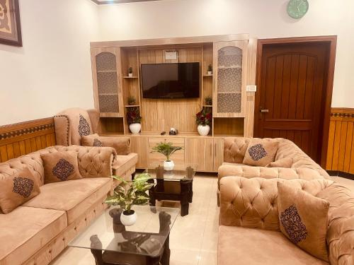 a living room with couches and a flat screen tv at Britannia House near Islamabad International Airport and Motorway in Islamabad