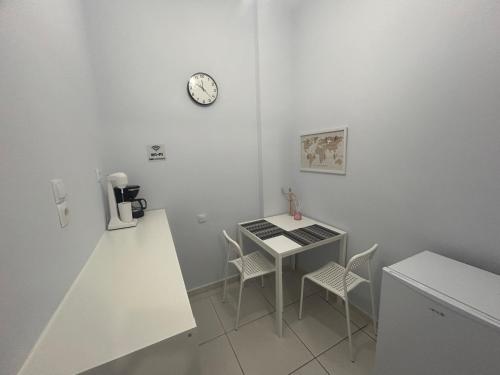 una cocina con mesa y sillas y un reloj en la pared en ΑKTIS apartment 2 near airport, en Artemida
