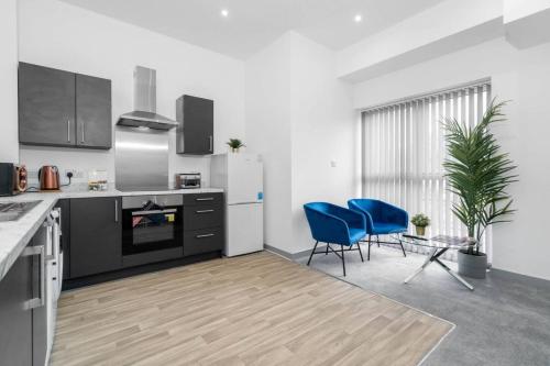 a kitchen with two blue chairs and a refrigerator at Modern Apartment - Twin Beds - Free Netflix & Wifi - Parking - Top Rated - 7OC in Brierley Hill