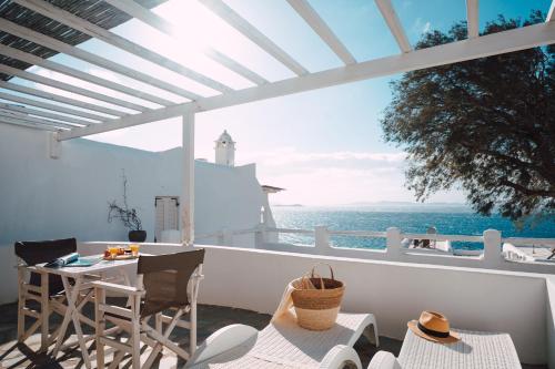 a balcony with a table and chairs and a view of the ocean at With-inn Mykonos Suites in Tourlos