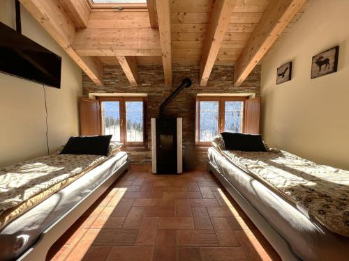 two beds in a room with wooden ceilings and windows at Affittimoderni Ponte di Legno Ski in Ponte di Legno