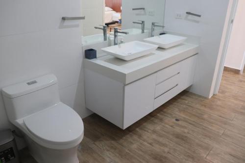 ein weißes Badezimmer mit zwei Waschbecken und einer Toilette in der Unterkunft Casa Z Paracas in Paracas