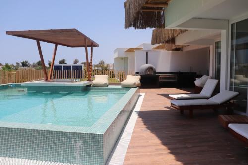 ein großer Swimmingpool mit Stühlen und einem Haus in der Unterkunft Casa Z Paracas in Paracas
