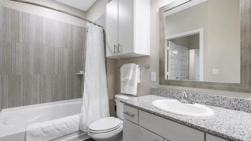 a white bathroom with a sink and a toilet and a tub at Landing - Modern Apartment with Amazing Amenities (ID8830X56) in San Antonio