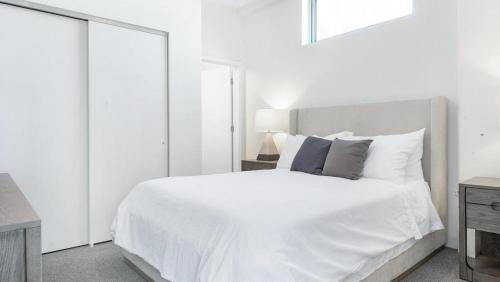 een witte slaapkamer met een groot wit bed en spiegels bij Landing - Modern Apartment with Amazing Amenities (ID8715X53) in Tower Grove