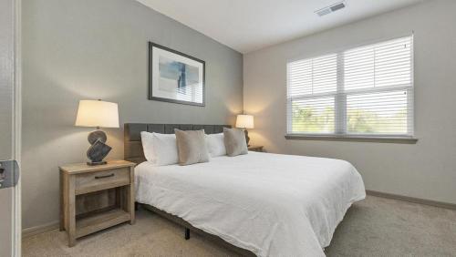 1 dormitorio con 1 cama blanca con lámpara y ventana en Landing - Modern Apartment with Amazing Amenities (ID3425X37), en Bradenton