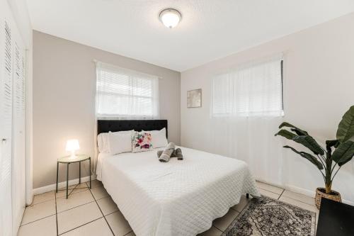 a white bedroom with a bed and a plant at Stylish 2 Bedroom Apartment In The Heart Of Miami in Miami