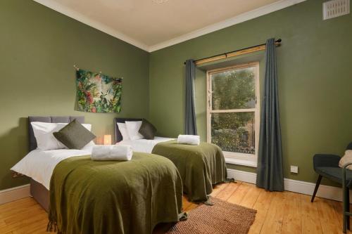 a bedroom with two beds with green walls and a window at Cosy, Stylish, Leafy And Homely in Sheffield