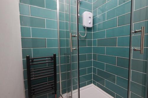 La salle de bains est pourvue d'une douche avec du carrelage bleu. dans l'établissement Cosy, Stylish, Leafy And Homely, à Sheffield