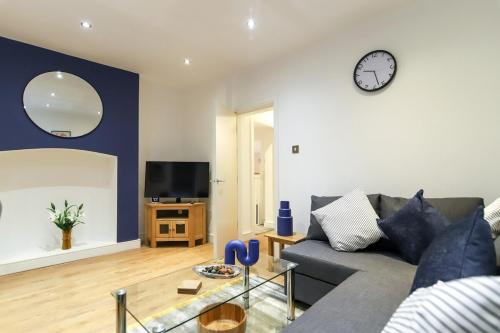 ein Wohnzimmer mit einem Sofa und einer Uhr an der Wand in der Unterkunft New- Modern 2br Apt Wifi Sleep5 City Centre in Sheffield