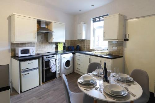 een keuken met een tafel en stoelen en een keuken met witte apparatuur bij Beautiful 3 Bedroom House - Sleeps 5 Free Parking in Longley
