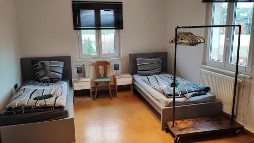 a room with two beds and a chair and windows at Monteurwohnung bis zu 10 Personen mit 5 großen gratis Parkplätzen und WLAN in Veitshöchheim