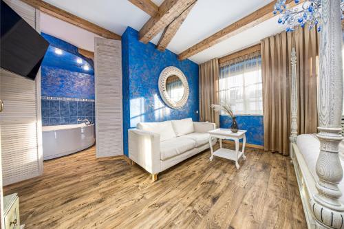 a living room with blue walls and a couch and a tub at Kurpiai - Suites & SPA in Klaipėda