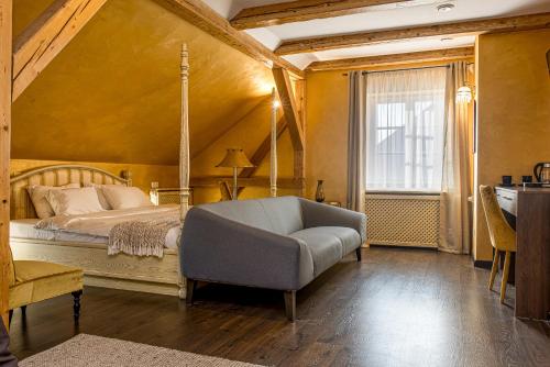 um quarto com uma cama, um sofá e uma janela em Kurpiai - Suites & SPA em Klaipėda