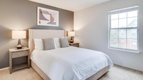 una camera bianca con un letto e due lampade di Landing - Modern Apartment with Amazing Amenities (ID7851X76) a Buffalo Grove