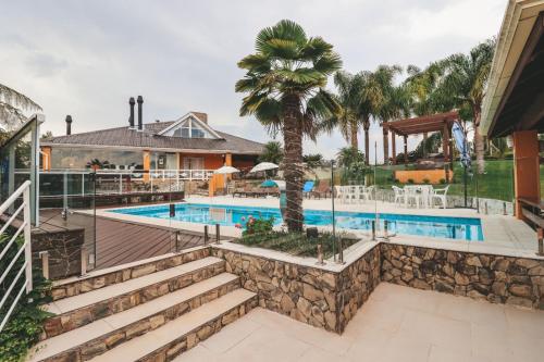 a house with a swimming pool and a palm tree at Paraíso do Salto in Lages
