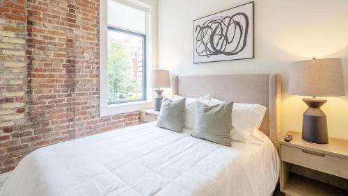 a bedroom with a white bed with a brick wall at Landing - Modern Apartment with Amazing Amenities (ID5790X33) in Birmingham