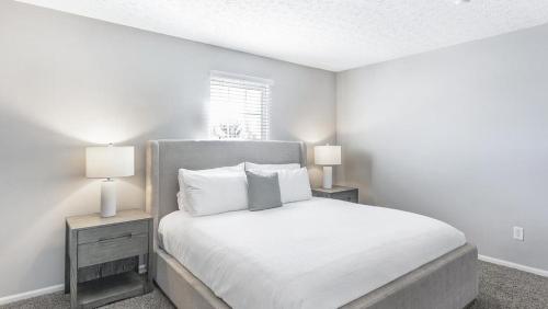 a white bedroom with a bed with two lamps at Landing - Modern Apartment with Amazing Amenities (ID9303X46) in Lewis Center