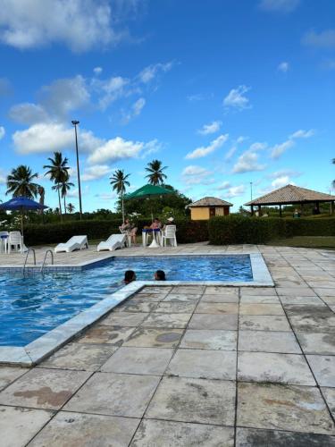 a pool at a resort with palm trees in the background at Gavoa Resort Flat - Mar Doce Lar in Igarassu