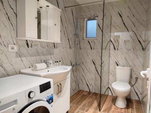 a bathroom with a toilet sink and a washing machine at Four Seasons Apartments in Ksamil