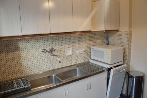une cuisine avec un évier et un micro-ondes dans l'établissement Appartement climatisé à 100m de la plage 122, à Cavalaire-sur-Mer