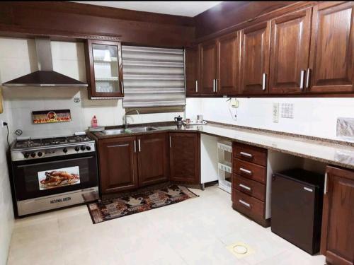a kitchen with wooden cabinets and a stove top oven at Pomegranate Tree in Wadi Musa