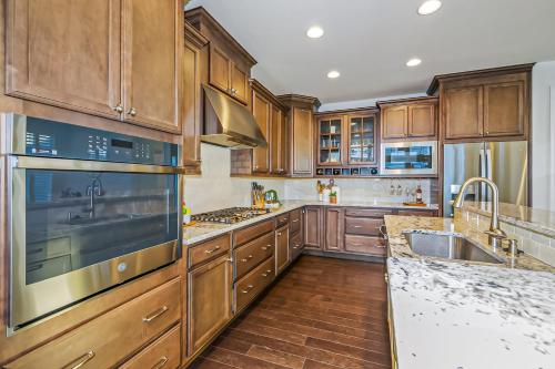 a kitchen with wooden cabinets and stainless steel appliances at The Peninsula --- 24647 Navigators Walk in Millsboro