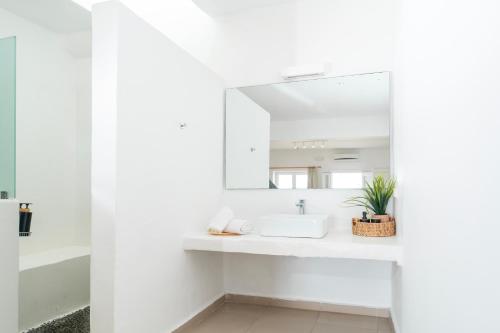 a white bathroom with a sink and a mirror at With-inn Mykonos Suites in Tourlos