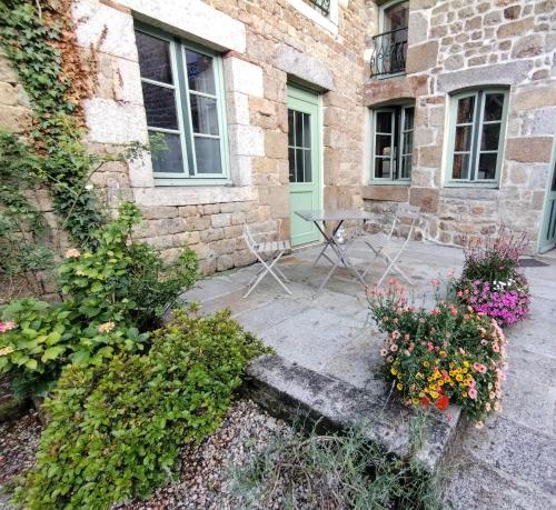 Carrouges的住宿－Le cheval blanc，一座建筑前带桌子和鲜花的庭院