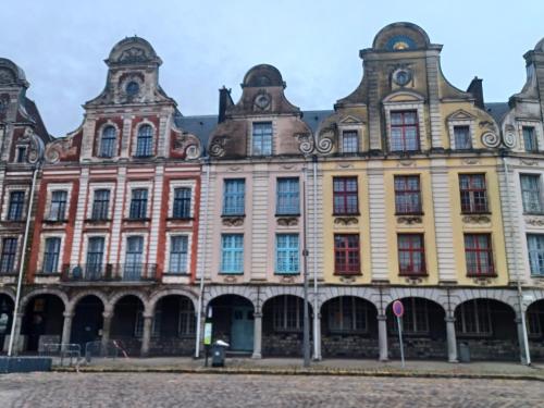 Au cœur de la Grand Place في أراس: مبنى كبير مع العديد من النوافذ على شارع