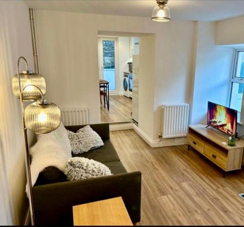 a living room with a couch and a tv at The Cottage, Bridge House in Laxey