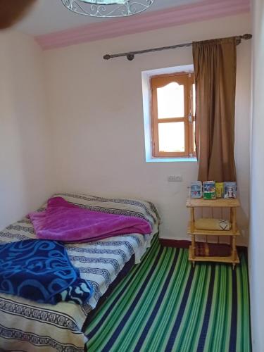 a small bedroom with a bed and a window at Maison d'Hôtes Agdal Telouet in Tiguidert