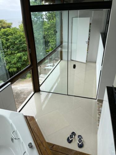 a glass shower in a bathroom with shoes on the floor at CASA DE TUCA in Ilhabela