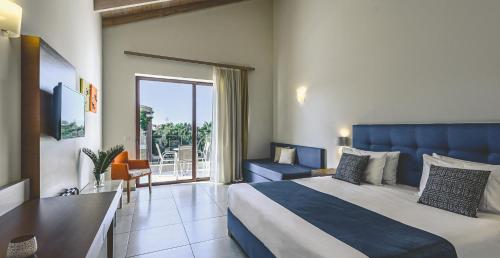 a hotel room with a bed and a balcony at Althea Village - Family Hotel in Kato Daratso