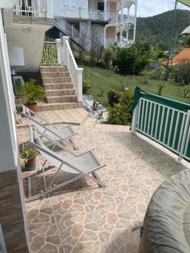 a patio with two lawn chairs and a staircase at Chez Maïté in Terre-de-Bas