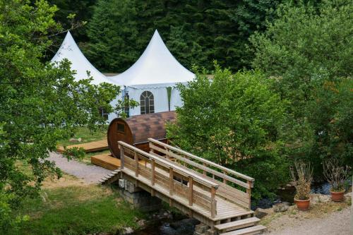 Les Jardins du Nideck في Oberhaslach: خيمة بيضاء فيها جسر خشبي واشجار