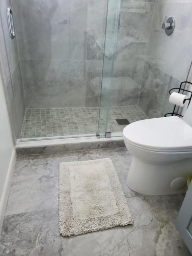 a bathroom with a shower with a toilet and a rug at Cozy family home in quiet area, nice garden views. in Tamiami